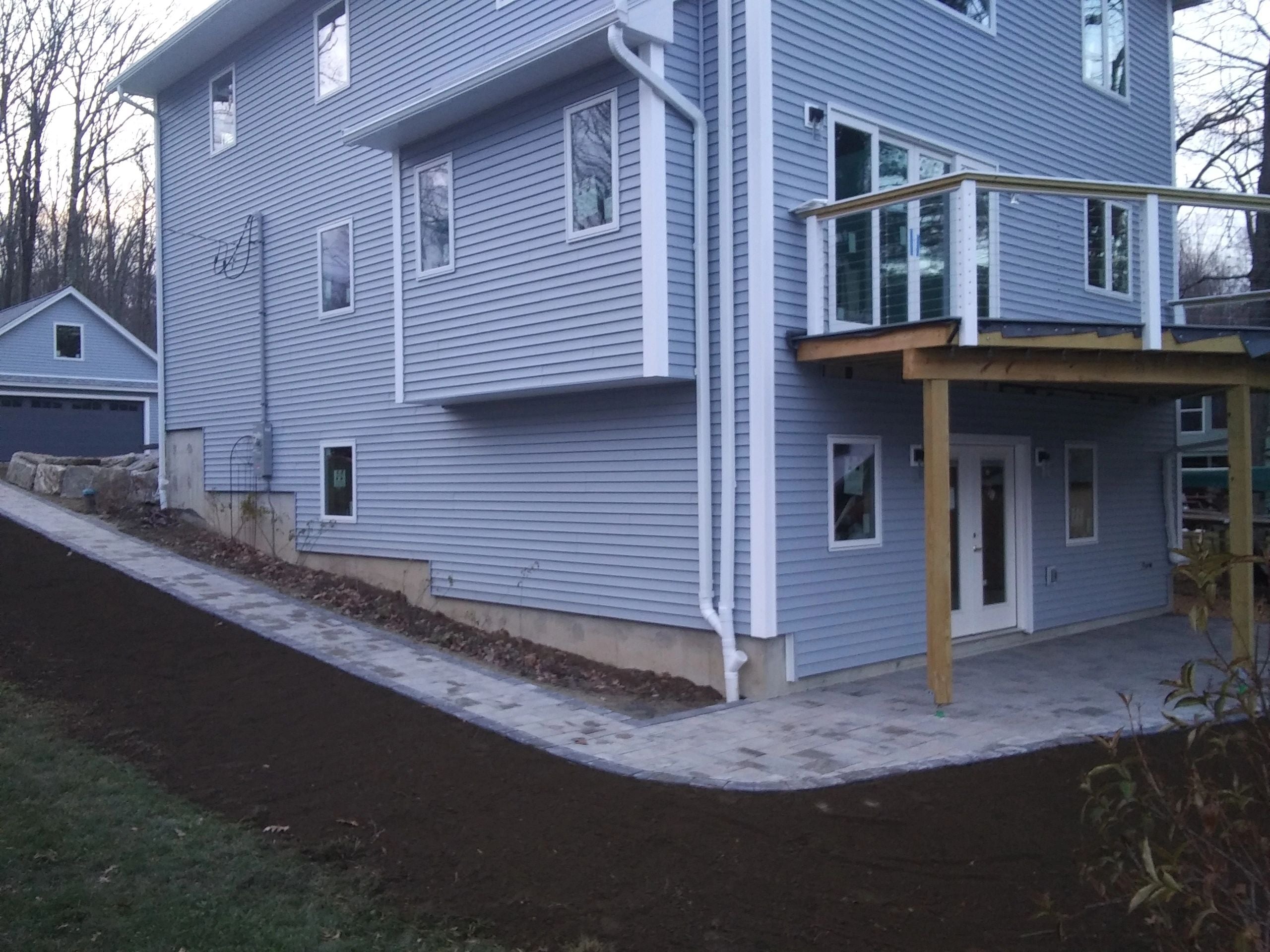 Completed paver walkway and patio at a Charlton lake house, with fresh landscaping and a view of the lake. Project by KRD Landscaping.