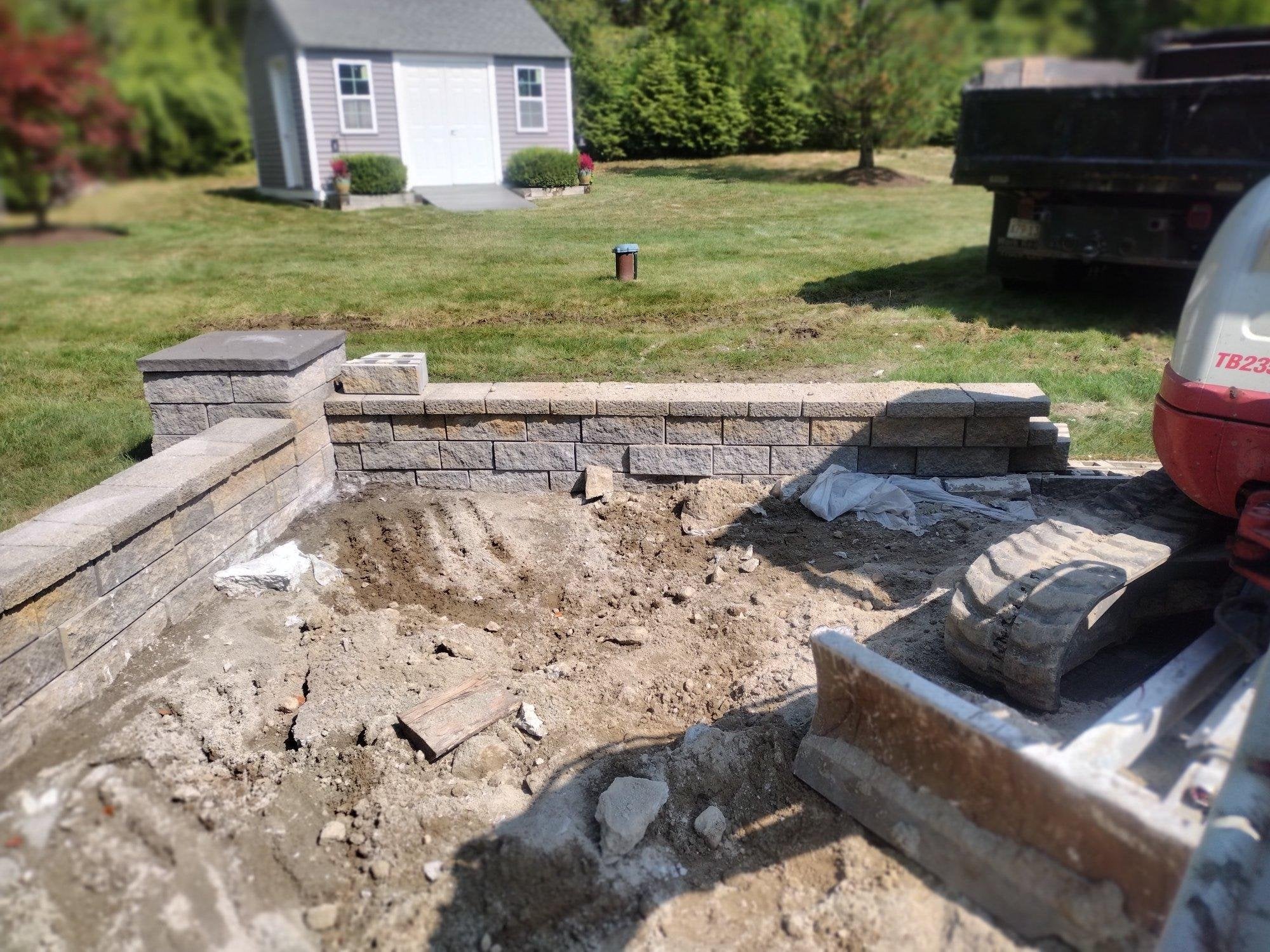 Completed large format herringbone paver patio with segmental block seat walls and decorative caps in backyard, installed by KRD Landscaping in Luster, MA.