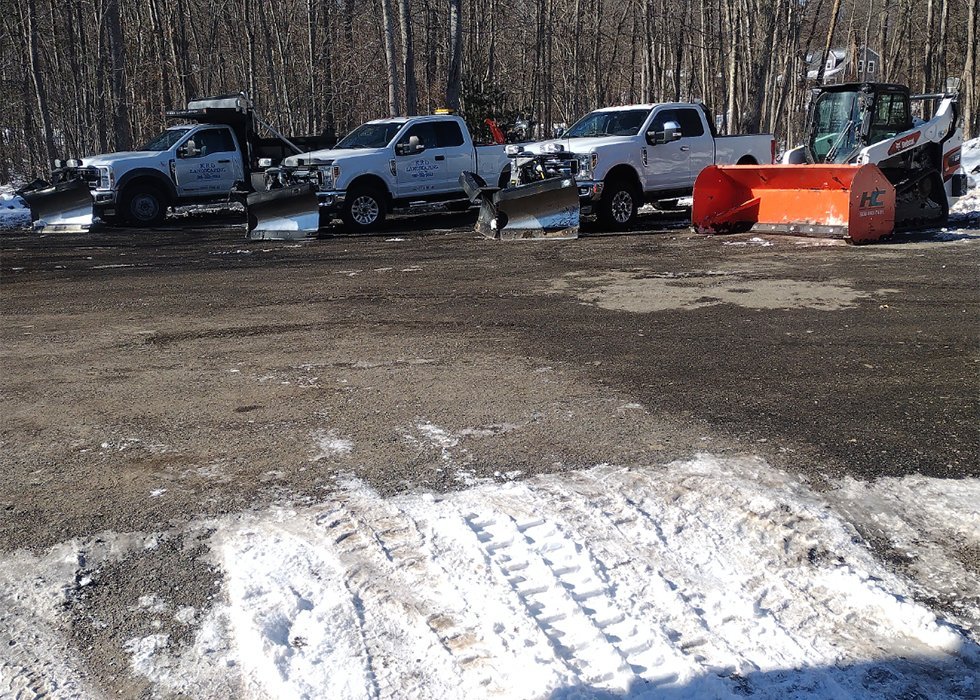 KRD Landscaping fleet of plow trucks and skid steer staged for commercial and residential snow plowing in Massachusetts