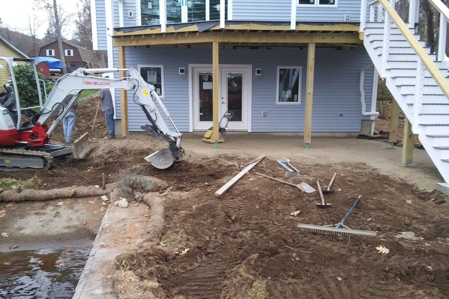 KRD Landscaping mini excavator grading and cleaning up a backyard during a landscape renovation at a waterfront property in Massachusetts