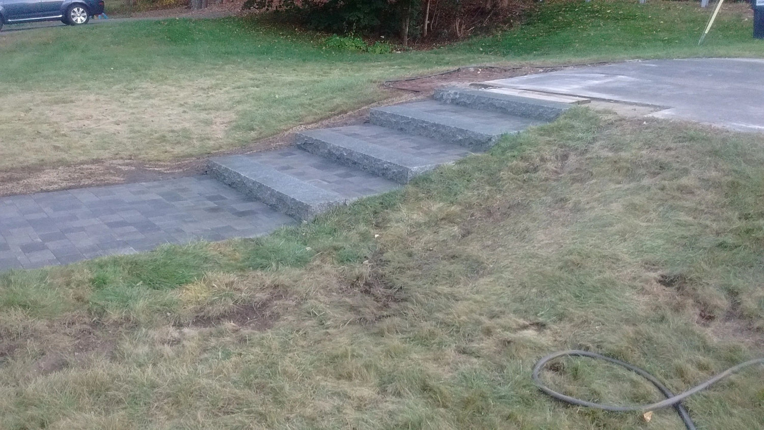 New granite steps and paver landing installed by KRD Landscaping connecting a driveway to a residential property in Massachusetts